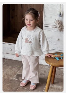 Close-up of girls' grey sweatshirt with bear print and pink pants featuring bow details