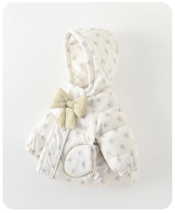 Détail d'une veste d'hiver fleurie pour bébé avec noeud jaune et poche ronde