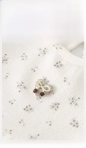 Detailed view of floral waffle fabric featuring heart embroidery and bow accent for babies