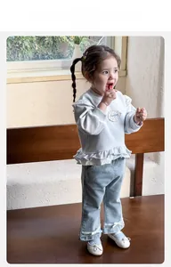 Detail of baby girl outfit showing ruffle hem sweatshirt and lace-trimmed denim pants