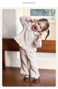 Détails de l'ensemble bébé fille avec haut à col Peter Pan et pantalon crème
