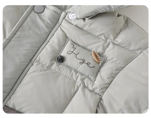 Detailed close-up of quilted winter jacket with metal buttons and Hope embroidery