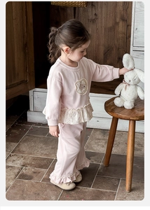 Detail of pink toddler girl tracksuit featuring floral ruffle hem and round patch embroidery