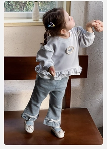Detail of girl's grey sweatshirt with lace hem and denim flared pants with bows