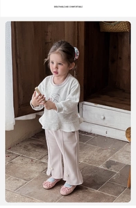 Detail of toddler girl outfit with ruffled hem sweatshirt and flared pants with pearl buttons