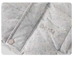 Macro detail of gray quilted fabric with liberta embroidery and button fastener