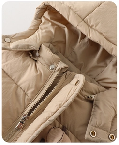 Close-up of beige baby winter jacket showing quilted fabric with metal zipper and snap buttons