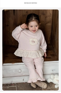 Detail of pink toddler sweatshirt featuring lace floral patch and ruffle hem design