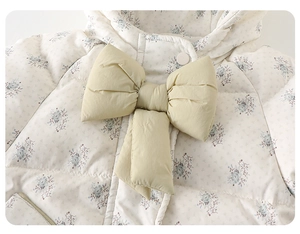 Détail de la veste d'hiver à fleurs pour bébé avec nœud vert clair et matelassage