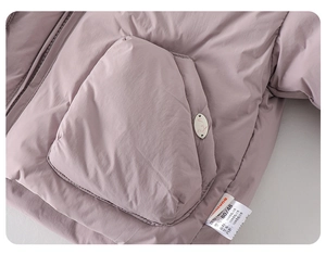 Detail of baby winter puffer coat showing soft purple fabric, pocket, and brand tag