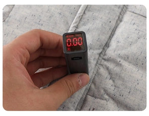 Handheld fluorescence detector showing zero reading on textured baby fabric garment