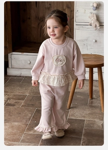 Detail of pink toddler set showing floral ruffle hem and delicate round embroidery patch