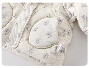 Détail de la veste matelassée fleurie pour bébé fille avec poche ronde et boutons-pression