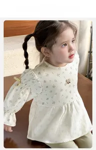 Detail of floral baby girl dress featuring yellow bows and delicate cotton texture