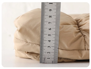Close-up of beige quilted winter jacket showing 9cm thickness with a ruler measurement