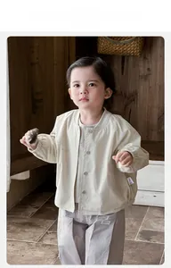Detail of baby beige cotton jacket featuring button closure and elastic cuffs for comfort