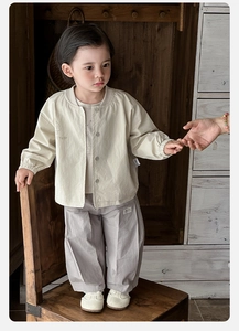 Close-up of beige cotton jacket with Voyage print and purple wide-leg pants for infants