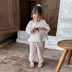 Girls' spring outfit featuring a cream ruffle sweatshirt and pink bow flare pants