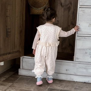 Barboteuse bébé à fleurs roses avec dentelle et volants dans un décor chaleureux