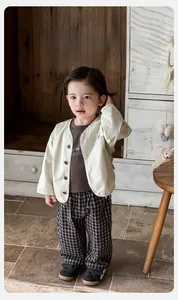 Three-piece baby boy outfit with beige cardigan, grey t-shirt, and checkered pants