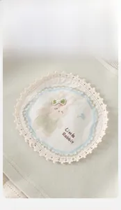 Détail d'un sweat pour bébé avec écusson lapin rond et bordure en dentelle beige