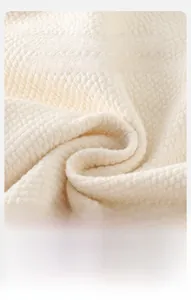Gros plan du tissu gaufré crème montrant une texture douce et respirante pour bébés