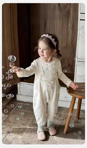 Detail of baby girl floral overalls set with ruffled collar and crown headband detail