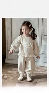 Détail du sweat-shirt crème pour filles avec bordure en dentelle et écusson dessin