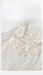 Detail of floral baby overalls with yellow chick patterns and lace ruffle trimming