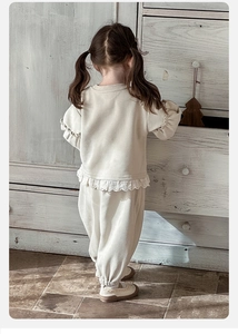 Détail d'un ensemble en coton crème pour bébé avec dentelle délicate sur l'ourlet et poignets
