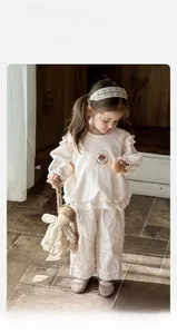 Détail de la broderie de champignon sur haut crème gaufré avec pantalon fleuri