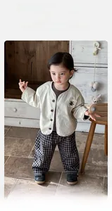 Detail of baby boy beige cotton jacket with animal patch and plaid wide-leg trousers
