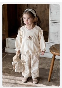 Détail du haut gaufré crème avec broderie champignon et pantalon fleuri pour bébé