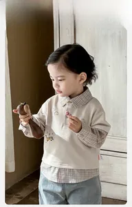 Detail of baby boy's beige patchwork polo shirt with plaid collar and cotton fabric