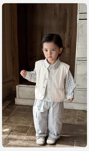 Détail de l'ensemble trois pièces pour bébé avec gilet crème, chemise et pantalon