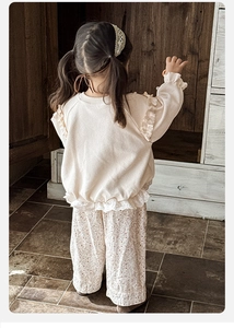 Détail du haut gaufré crème avec volants en dentelle et pantalon fleuri pour fille