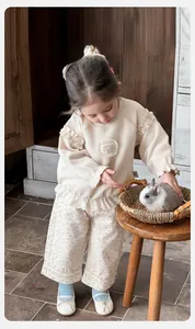 Dettaglio felpa color crema con volant e pantaloni floreali per bambine piccole