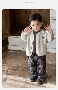 Detail of baby boy beige cardigan with wooden buttons and plaid trousers outfit