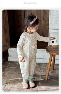 Close-up of baby girl floral overalls set with ruffled collar and soft cotton texture