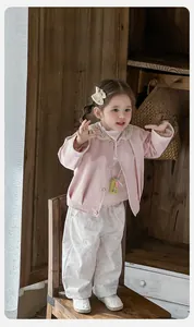 Détail de la veste rose pour petite fille avec col en dentelle et pantalon à fleurs doux