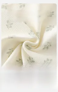 Close-up of soft ribbed baby fabric with green leaf prints and breathable texture