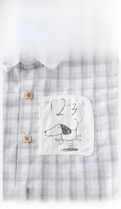 Détail d'une chemise à carreaux pour bébé avec boutons en bois et broderie de chien
