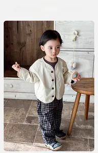 Detailed flat lay of baby boy spring outfit with beige cardigan and plaid pants