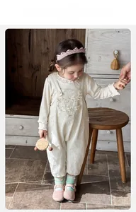 Close-up of floral baby jumpsuit set with lace collar and wooden buttons on cotton fabric