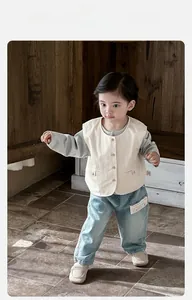 Detail of baby boy's spring 3-piece set with cream vest and light blue denim trousers