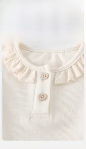 Dettaglio della maglia a coste per neonata con colletto in pizzo e bottoni