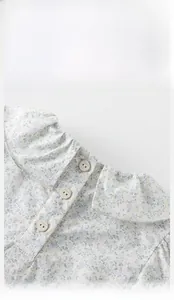 Detail of floral baby girl top featuring a ruffled Peter Pan collar and button closure