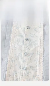 Dettaglio della giacca blu per neonata con toppa floreale e bordo in pizzo bianco