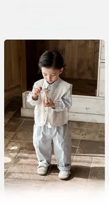 Détail de l'ensemble trois pièces pour bébé avec gilet beige, chemise et pantalon cargo