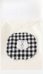 Detail of baby cream rib-knit shirt with checkered patch and bear embroidery